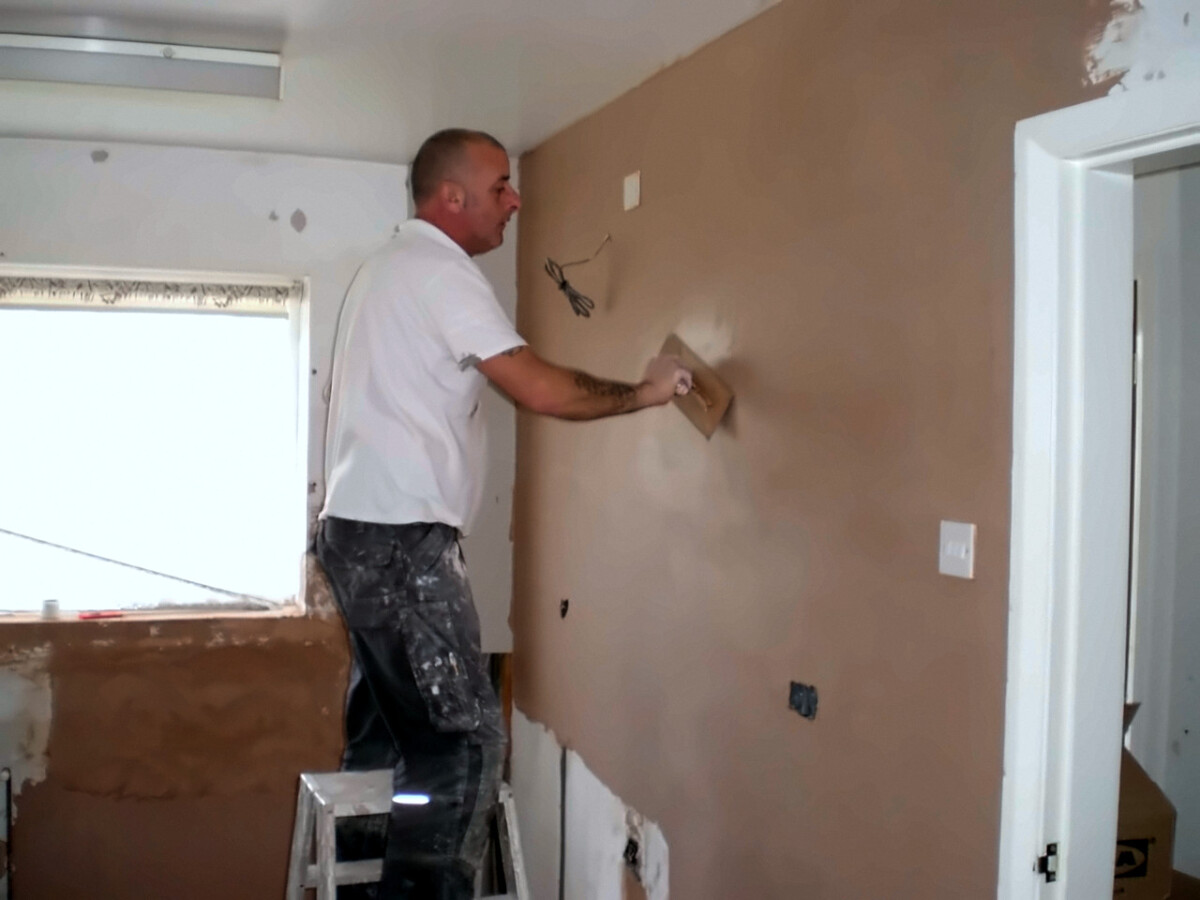 Paul Hughes plastering a living room wall